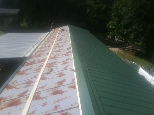 Old rusted panels beside newly installed green metal roofing — Wind Damage Roof Repair by Roofing Brothers in Connelly