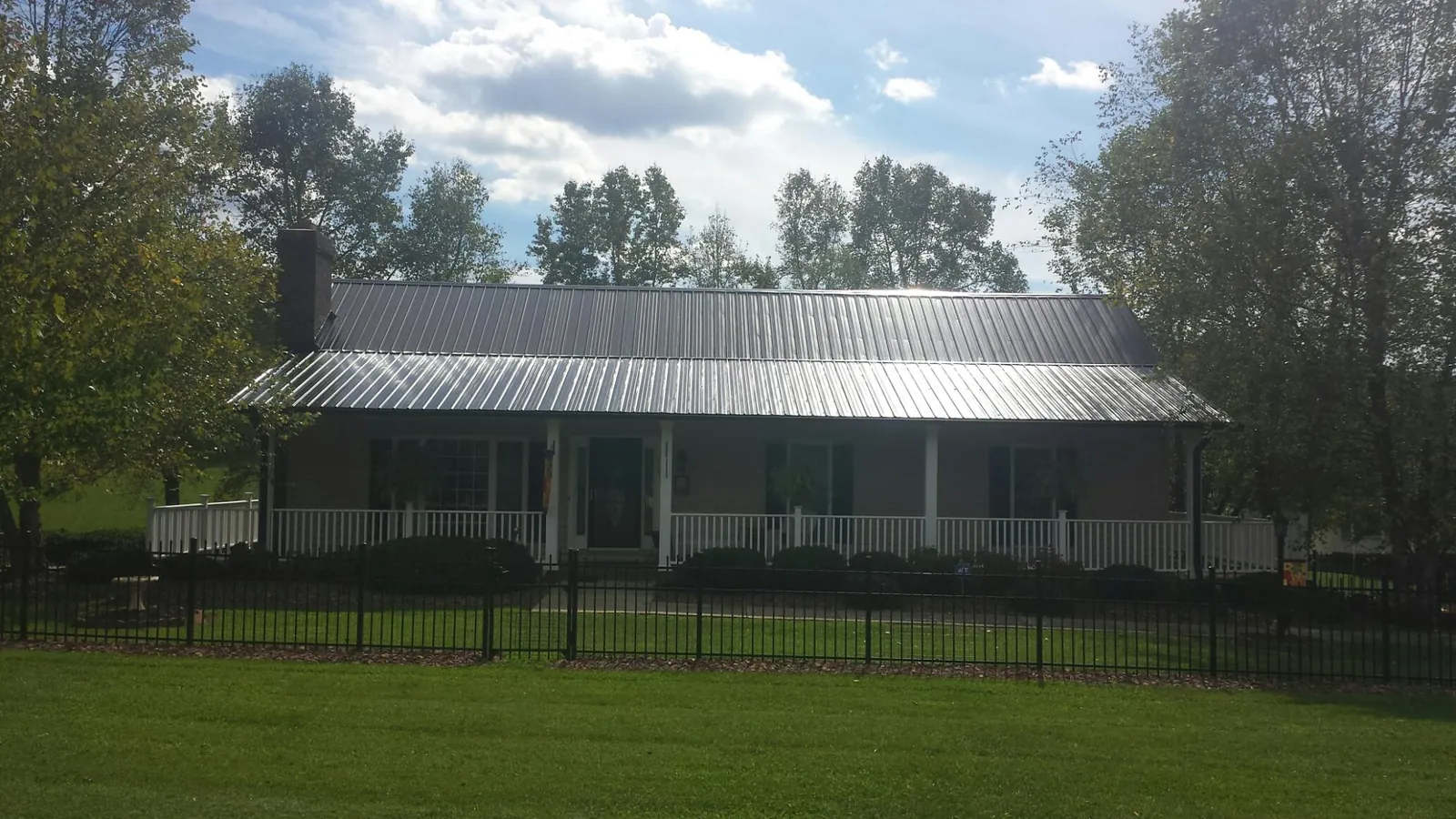Gray metal roof on a brick ranch with a full width front porch — Gutter Guard Installation work by our crew in Connelly
