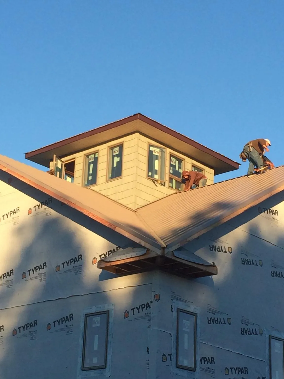 Roofers working around a rooftop cupola on a new metal roof at sunset — Roof Waterproofing in Connelly by Roofing Brothers